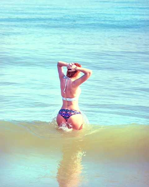 Mooi meisje in bikini poseren op een verlaten strand. wit zand, turquoise zee en een jong meisje. — Stockfoto