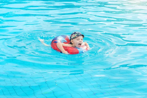 Kisfiú úszik, vidám gyermek Ugrás a medencében, a kör, szabadtéri úszómedence, — Stock Fotó