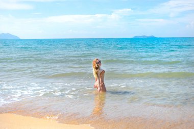 güzel kız bikini ıssız bir sahilde poz. beyaz kum, turkuaz deniz ve bir genç kız.