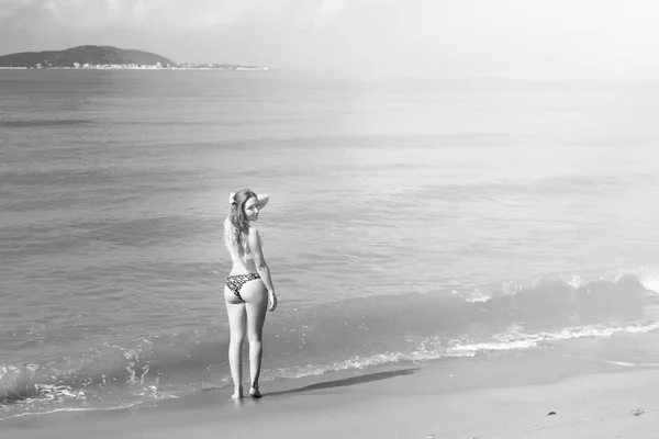 Beautiful girl in bikini posing on a deserted beach. white sand, turquoise sea and a young girl. — Stock Photo, Image