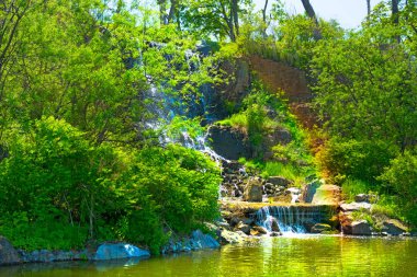 güneş ışığı, yeşil ormanlarla çevrili çok güzel su jetleri altında güzel şelale. 