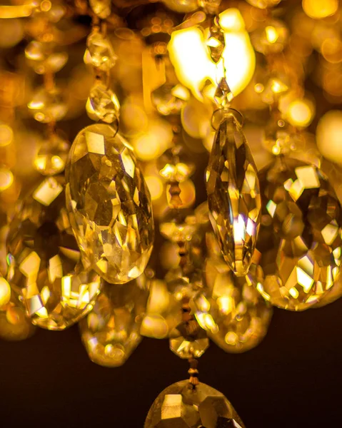 Beautiful, bright chandelier, lots of large colorful crystals. Wisps of light in the chandelier hanging on the ceiling. — Stock Photo, Image