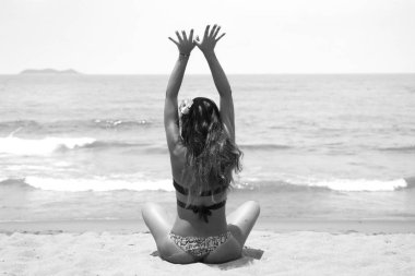 bir bikini kırmızı saçlı Genç, güzel bir kız. beyaz kum ve turkuaz denizin üzerinde Yoga uygulamaları.