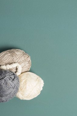 Lana bej y gris en una esquina de fondo verde