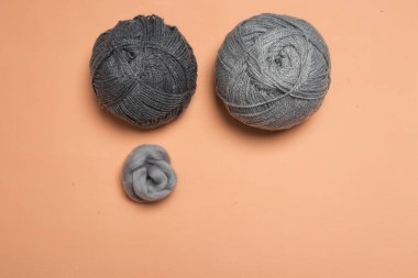 Lanas bej en tonos de gris en fondo coral en canasta de madera