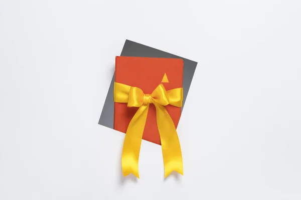 Cuaderno con cinta de regalo saliendo de marco sobre fondo blanco