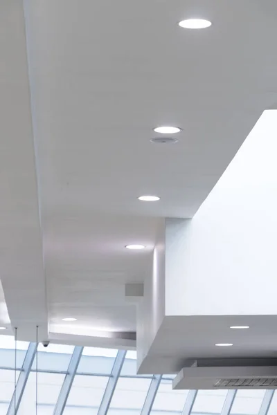 Techo blanco asimtrico con luces daireselinin crustadas blancas en perspectiva y ventana diyagonal con luz blanca
