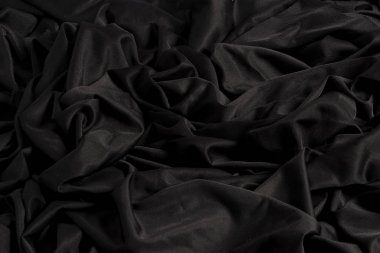 Tela negra brillante con ondulaciones y textura con luz dura y claro oscuro