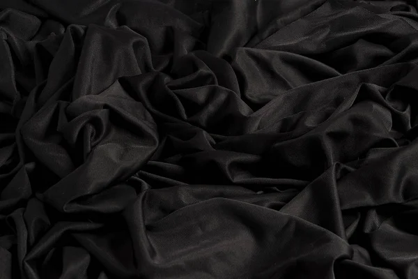 Tela negra brillante con ondulaciones y textura con luz dura y claro oscuro