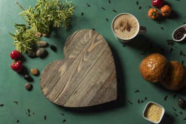 Corazon en madera con bebida de çikolata caliente sobre fondo verde y luz dura