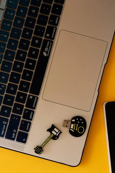 Disko iade edilebilir usb en forma de guitarra al lado de un comparo porttil y mesa amarilla