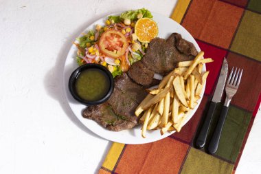 Plato de comida con carne de res ensalada y papas a la francesa. Almuerzo geleneksel olarak Latinoamerica de carne con papas y chimichurri