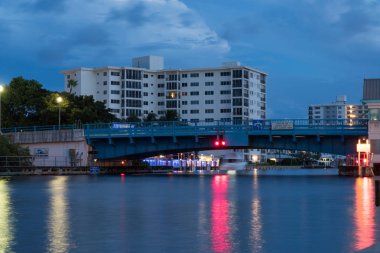 Uzun gece zaman pozlama tekne geçen genel Florida ABD kıyı kenti içinde asma köprü altında. Genel yüksek doğmak lüks apartman arka planda