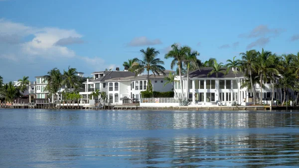 Typical luxury riverfront summer homes along quiet river in tropical southern location on beautiful summer day. Exterior generic establishing shot