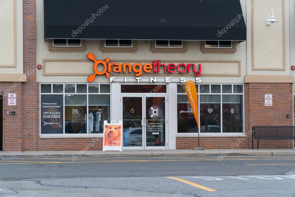 New York, USA - Circa 2018: Orange Theory Fitness exterior gym studio store front franchise facade and sign. View from parking lot. Heart rate interval group training concept