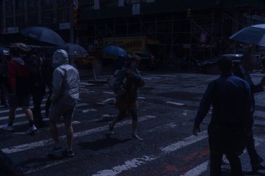 New York City, Circa 2019: Yağmurda akşam gidip sırasında Manhattan yaya geçidinin gece görüş. Poncho ve şemsiye kaplamaları yayalar kuru tutmak