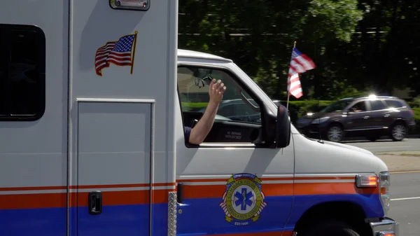 ロングアイランド ニューヨーク Circa 2019 救急車の緊急車両は 夏の日の間に記念日のパレードで運転をクローズアップアメリカの自由と名誉軍隊を祝います 窓から手と旗を振る — ストック写真