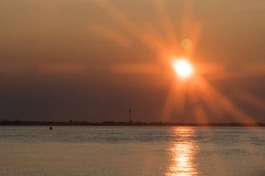 Suyun üzerindeki güzel turuncu günbatımı ışık yansıması etkisi ile atmosfere ışınlar saçıyor.