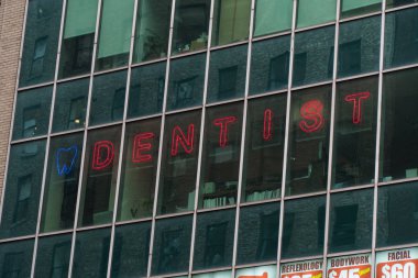 Büyük şehir merkezindeki ofis binasının vitrinindeki genel dişçi tabelası müşterileri çekmek ve ağız ve diş bakımı için tıbbi tesislerin reklamını yapmak için. 