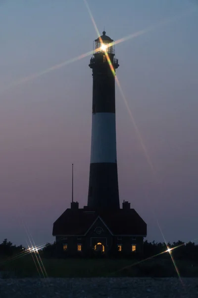 Fire Island lighthouse beacon cross star effect from beacon light shining over Robert Moses beach at night time signaling shoreline to ocean boats traveling in open waters