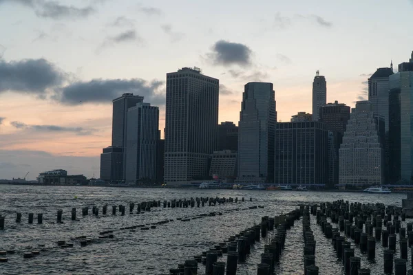 マンハッタンのダウンタウンの背後にある壮大な夕日の美しい広い景色ニューヨークの港に沈む夕日の金融街のスカイライン空を渡って色をキャスト — ストック写真