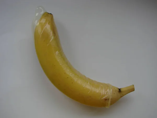 Sexo seguro com preservativo e sexo desprotegido levando a doença. Conceito. Banana sã em um preservativo — Fotografia de Stock