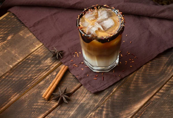 Ice coffee in a tall glass on a old rustic wooden table. Cold summer drink on a dark wooden background with copy space