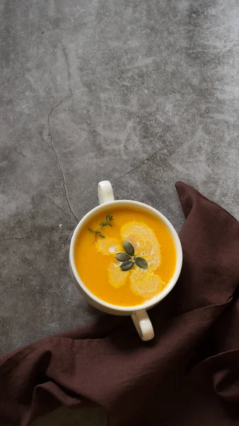 Pumpkin soup in a bowl with fresh seeds, cream on a gray background — Stock Photo, Image