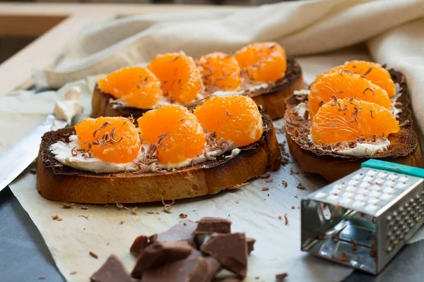 Siyah ahşap arka planda tatlı mandalina ve krem peynirli lezzetli tost. Boşluğu kopyala.