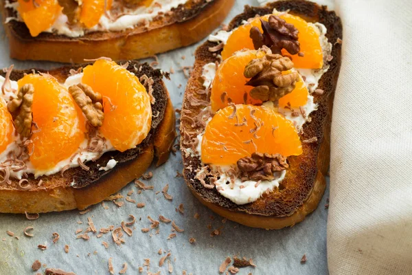 Siyah ahşap arka planda tatlı mandalina ve krem peynirli lezzetli tost. Boşluğu kopyala.