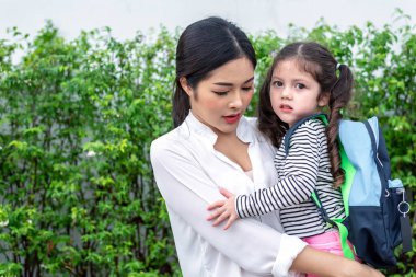 Anne okula gitmeden önce kızını taşıyor. Sevgi ve kreş konsepti. Mutlu aile ve Ev tatlı ev teması. Okula ve eğitim temaya geri dön.
