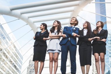 Portrait of successful group of business people looking up to sky as future. Happy businessmen and businesswomen team in satisfaction gesture. Successful group of people smiling in city background clipart