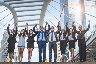 Portrait of successful group of business people at outdoor urban. Happy businessmen and businesswomen raising hand as team in satisfaction gesture. Successful group of people smiling after achievement clipart