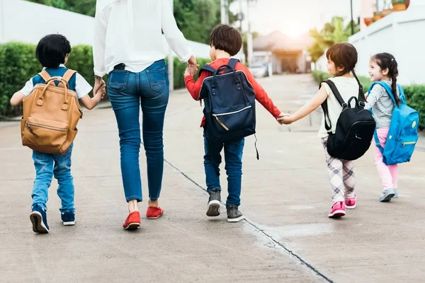 回到学校 学生妈妈一起上学 父母带着书包或书包一起送小男孩和小女孩去上第一学期的课 协作学习和移情日托 — 图库照片