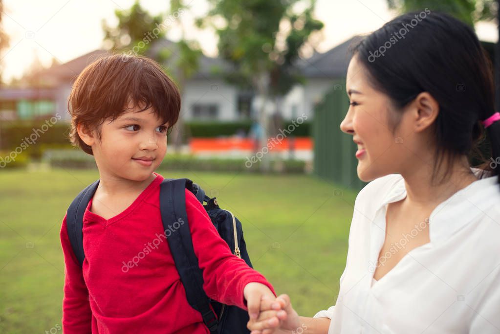 Mother and son holding hand during walking in park together. Loving family and Home sweet home concept.