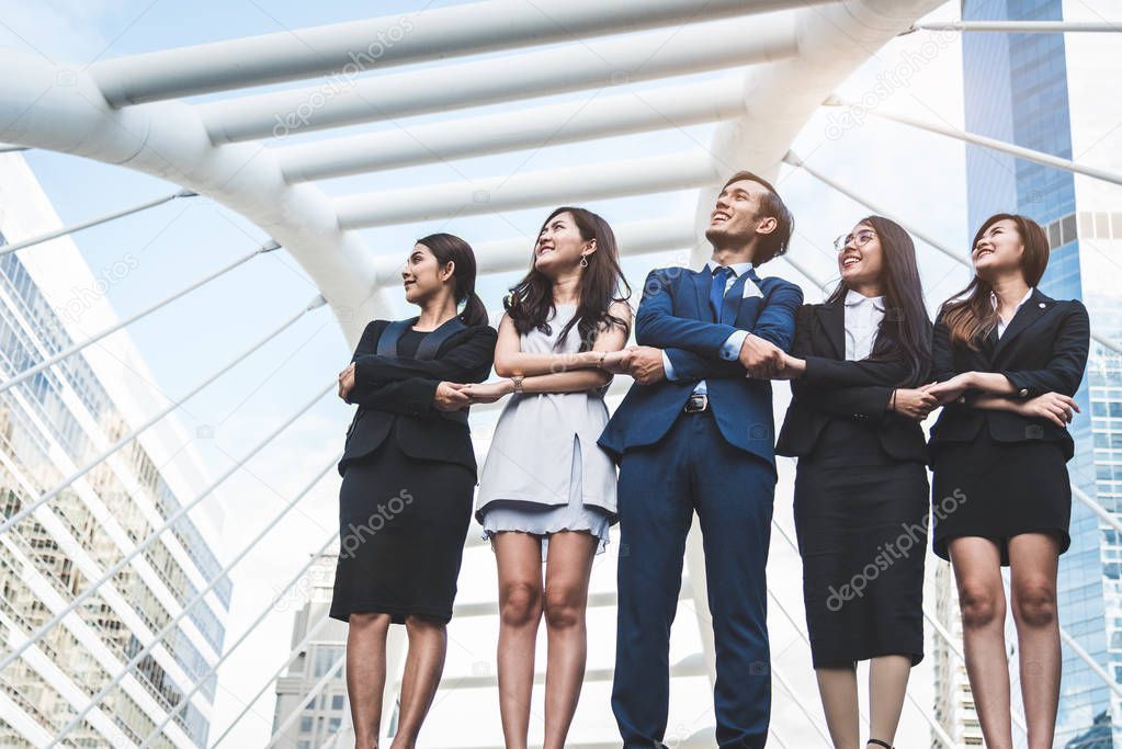 Portrait of successful group of business people looking up to sky as future. Happy businessmen and businesswomen team in satisfaction gesture. Successful group of people smiling in city background