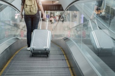 Bagaj bavul uçak tarafından Dünya çapında olacak kadın gezgin alt beden kadar yakın. Havaalanı terminal otomatik yürüyen merdiven üzerinde kadın turist.