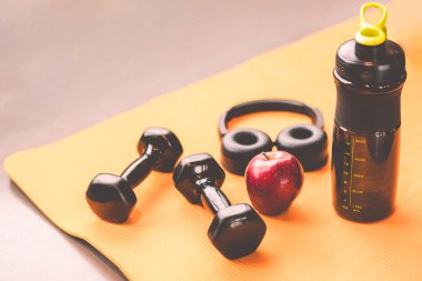 Egzersiz egzersiz ekipmanları spor salonu fitness spor Eğitim Merkezi'nde dumbbell ile. Kulaklık elma meyve ve protein şişe sallamak. Sağlık ve yaşam tarzı vücut geliştirme dinlenmek ve diyet kilo pervane kavramı