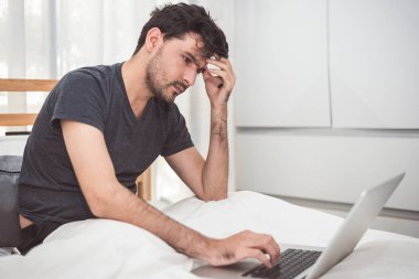 Yatak odasında dizüstü bilgisayar ile işten adam stresli. Teknoloji ve yaşam tarzı kavramı. Sosyal Konular ve sorun. Sağlık ve Office sendromu. Ekonomik kriz ve kritik son krizin Tema.