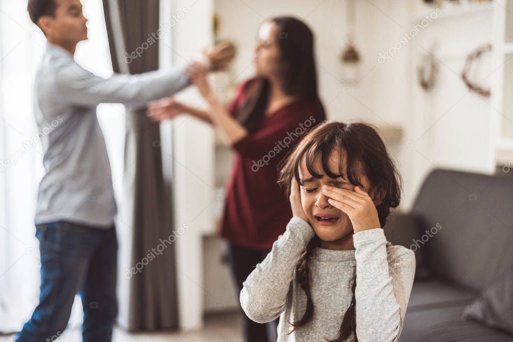 Little girl crying because of her parents quarreling. Girl abused with mother and father shouting and conflict angry background in home. Family dramatic scene, Family social issues problem concept.