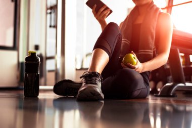 Kadın fitness spor olarak çalışma sırasında akıllı telefon ve holding elma kullanarak kapatın. Spor ve teknoloji kavramı. Yaşam tarzı ve sağlık Tema.