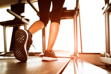 Arkadan daha düşük vücut bacaklar makine veya sun ray ile fitness salonunda koşu bandı üzerinde çalışan fitness kızın görünüşü. Sıcak sesi. Sağlıklı ve egzersiz etkinlik kavramı. Egzersiz ve gücü eğitim Tema.