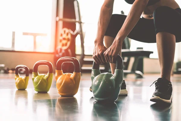 Kadın fitness spor kulübü spor eğitim merkezi spor cihazların yakınında pencere arka plan ile kettlebell halter gibi kaldırma kapatın. Vücut geliştirme ve sağlıklı yaşam tarzları ve egzersiz egzersiz