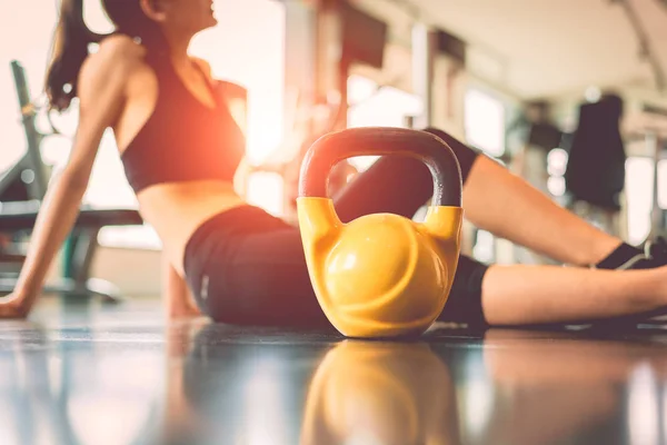 Close up kettlebells with woman exercise workout in gym fitness breaking relax after sport training center background. Healthy lifestyle bodybuilding and athlete muscle dumbbells. Healthcare lifestyle