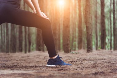 Yoga yaparken ve açık havada, ormandaki çalıştırmadan önce bacaklarını germe kadın daha düşük vücut yakın çekim. Spor ve doğa kavramı. Yaşam tarzı ve etkinlik kavramı. Çam ormanlar Tema.