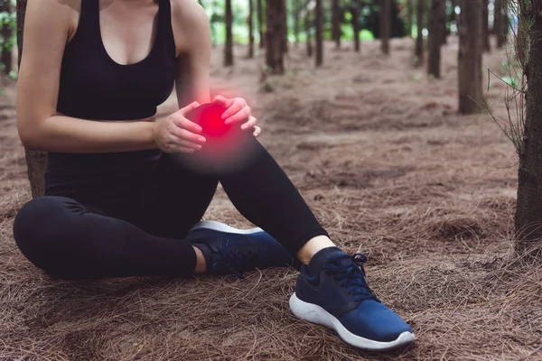 スポーツ女性森林でジョギング中に膝に傷害 松森背景 医療とヘルスケアの概念 自然と人々 のテーマ ライフ スタイルのテーマです 赤光スポット使用 — ストック写真