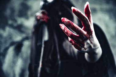 Kanlı el gösterilen cadı. Siyah giysiler ve grunge duvar arka plan kaputa dişi şeytan melek. Cadılar Bayramı gün ve gizem kavramı. Sihirli Tema fantezi. Ölümden sonra yaşam ve ölüm kavramı.