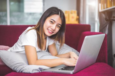 Genç kadın neşeli jest ruh duygu kırmızı kanepede dizüstü tarafından internette sörf. Satış ve online alışveriş kavramı. Tüccar ve pazarlama. Mutluluk yeni iş tüccar ve girişimci