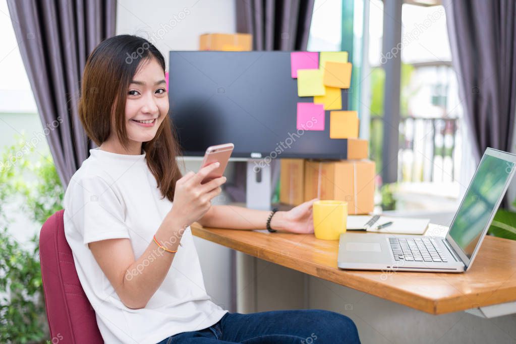 Asian woman enjoy herself while using  internet on laptop and phone in office. Business and marketing and part time concept. Online shopping and business success theme. Happy mood doing working job.