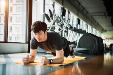 Asya fitness adam portresi spor salonunda planking egzersiz yapıyor. Pe